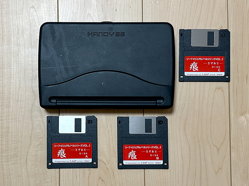 本体の大きさが分かるよう、比較対象として3.5インチFDと一緒に撮影してみました。非常に小さく、また単体であれば画面がほぼ180度近くまで開くようになっています。手前右下にはリセットスイッチがあり、爪楊枝など先が細いもので押すとリセットできました。画面の右側には、コントラスト調節つまみがあります。