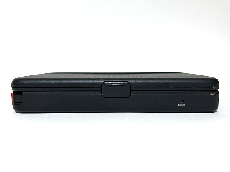 本体の大きさが分かるよう、比較対象として3.5インチFDと一緒に撮影してみました。非常に小さく、また単体であれば画面がほぼ180度近くまで開くようになっています。手前右下にはリセットスイッチがあり、爪楊枝など先が細いもので押すとリセットできました。画面の右側には、コントラスト調節つまみがあります。