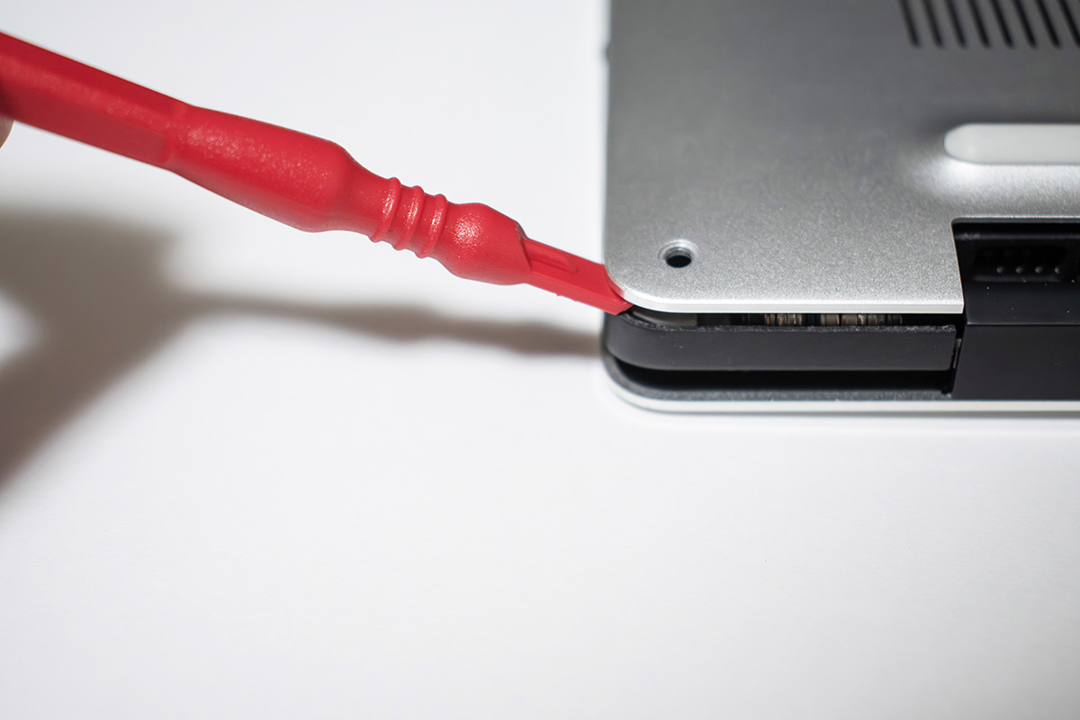 【3】ネジをすべて外したら、オープナーを角からゆっくり入れて慎重に開けよう