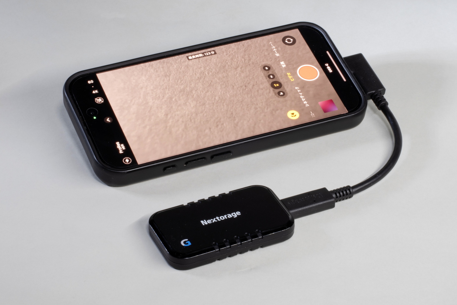 iPhone 16 Pro(保護ケース併用)とNX-P2SE2TB/Gを付属ケーブルで接続するとこんな感じになる。SSD自体が軽量なので、両方をまとめて片手で持ってもさほど苦はない