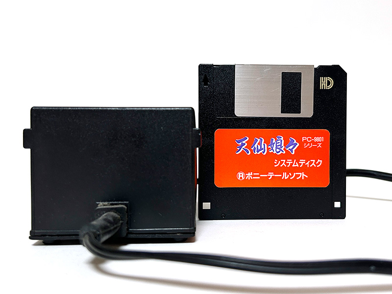 キーボードを、真上から撮影しました。このアングルでは少々のっぺりした感じに見えるかもしれませんが、スペースを除くキーは中央部分が少しだけふっくらと盛り上がっていて、押すと“ヘコッ”という感じで凹みます。スペースキーは反応がありませんが、軽く叩けばスペースが入力されました。電源は真上と真横から撮影しましたが、比較対象として3.5インチFDを置いています。これで、どの程度大きいのかが分かると思います。