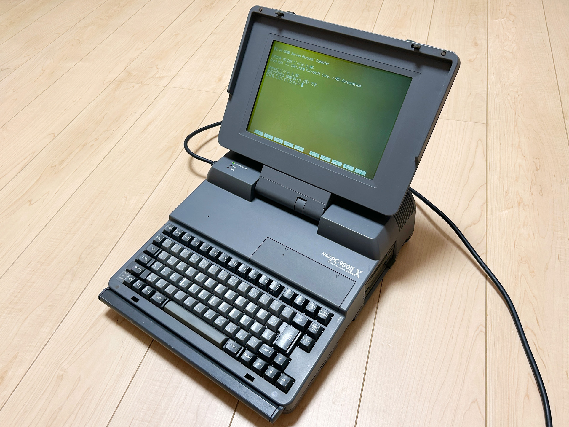 外見は、PC-9801LS2やPC-9801LV22といった機種とあまりかわりません。手前にある2つのスライドスイッチを左右にすぼめると爪が外れてモニタがガバリと奥に開き、写真の状態になります。持ち運ぶときのキャリングハンドルは、パームレストとしても機能しました。