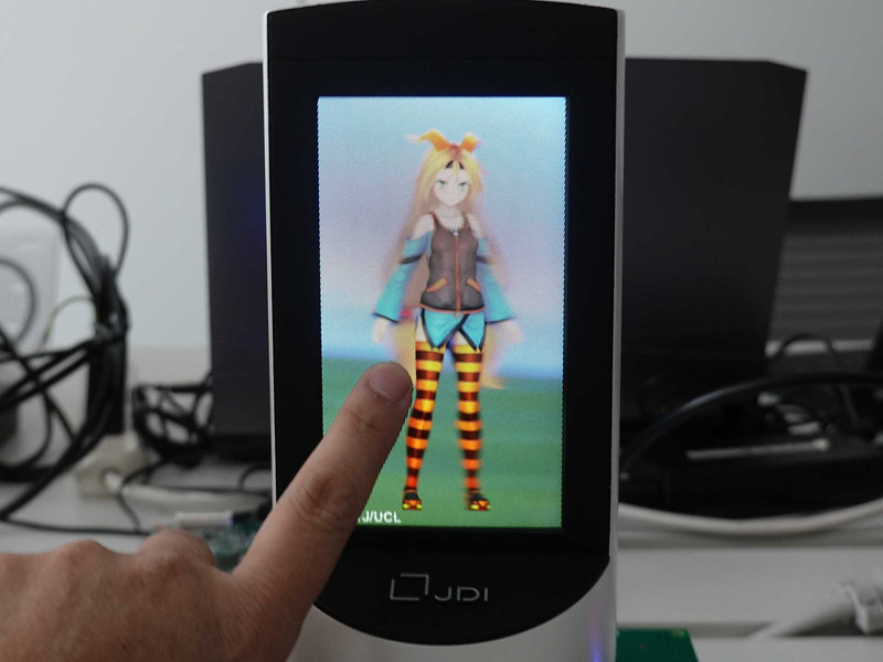 少しずつ角度を変えて撮影。立体感がわかりやすいよう、ディスプレイ面に指を置いてみた。これは「映像が少しずつ回っている」のではなく、見ている方向によってキャラクターの見える方向が少しずつ違う、ということだ