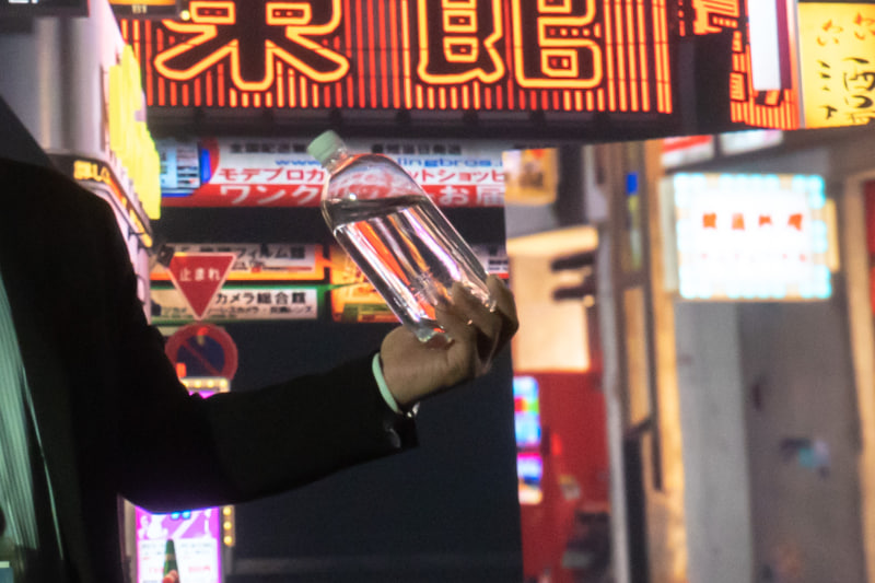 透明な水が入ったペットボトルを持って撮影。このように「背景の映像がちゃんと自然に映る」のは、グリーンバックではなかなか難しい