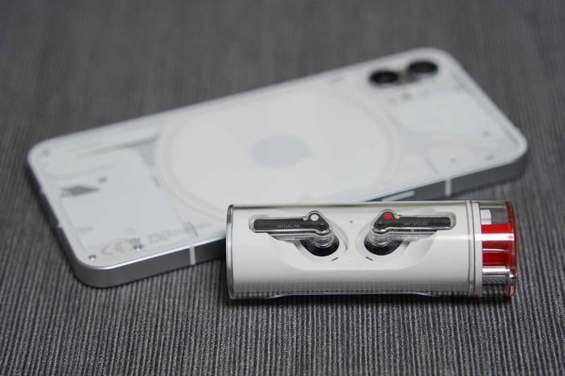 円筒状ケースが特徴的な「Nothing Ear (stick)」。後ろは同社のスマートフォン「Nothing Phone (1)」
