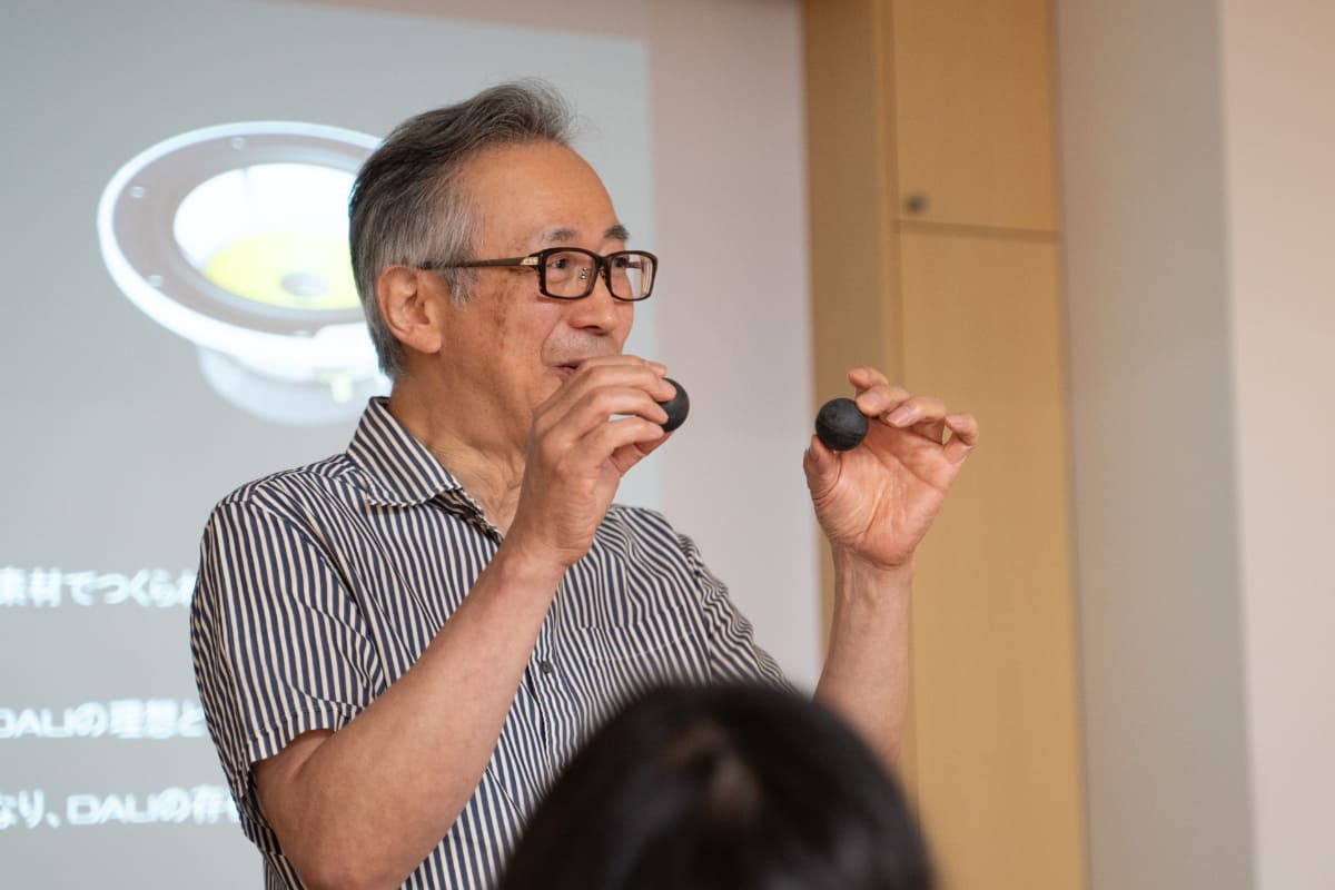 D&Mのシニアサウンドマスター・澤田龍一氏が2種類のゴムで実験。低反発なゴムは机に「ゴンッ」と落ちてあまり跳ねないが、DALIが採用している高反発系のゴムはかなり高く跳ね上がる