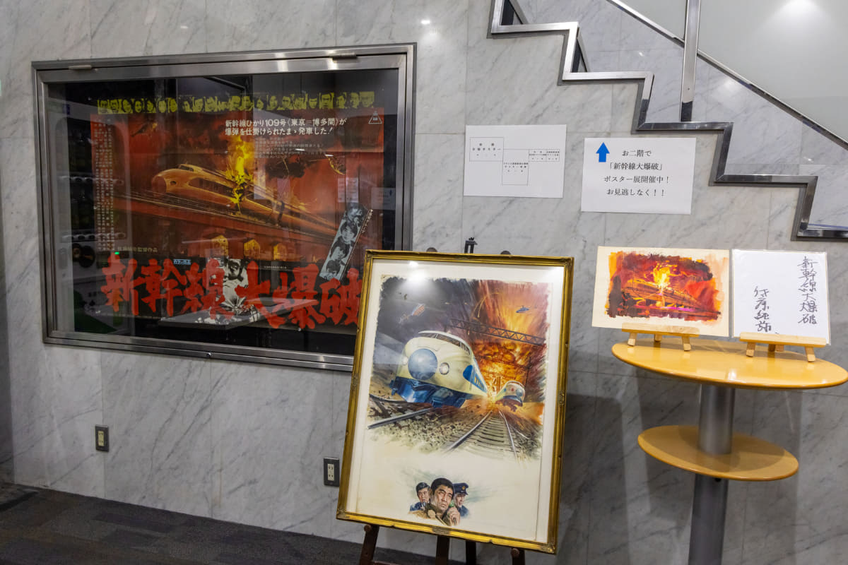 劇場ロビーや2階には、愛好家の方が集めた『新幹線大爆破』の各種ポスターが展示されていた。写真左から、初版ポスター、フランス語凱旋公開時のポスター原画、初版宣伝用ビジュアル原画、佐藤純彌監督サイン色紙