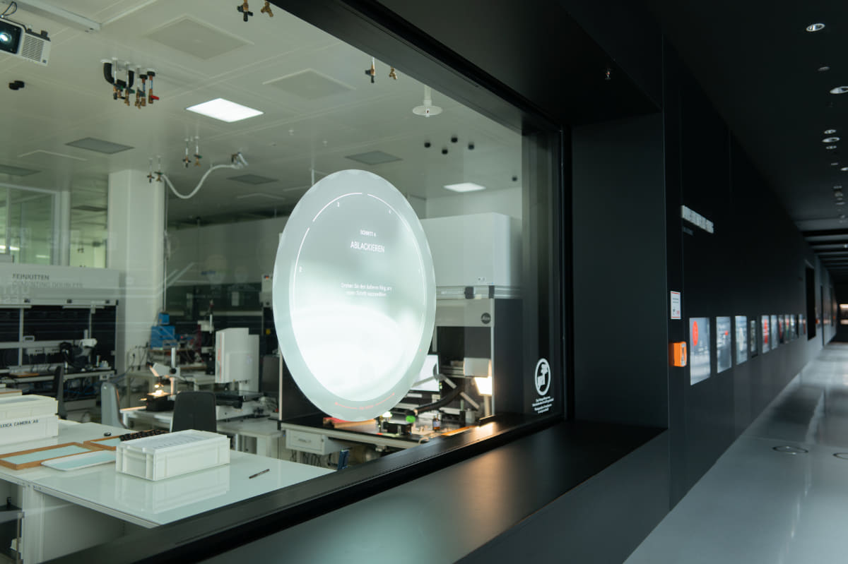 見学コースの入口。レンズの製造工程について、ガラスに投影された映像をタッチしながら学べる。