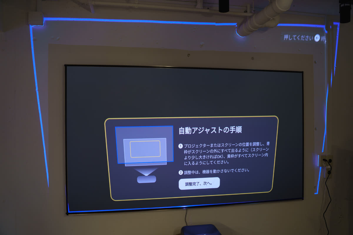 「自動スクリーンフィット」機能を試しているところ。プロジェクターがスクリーンの位置を認識し、そこにピッタリ収まるように投写してくれる