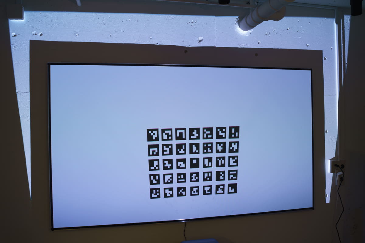 「自動スクリーンフィット」機能を試しているところ。プロジェクターがスクリーンの位置を認識し、そこにピッタリ収まるように投写してくれる