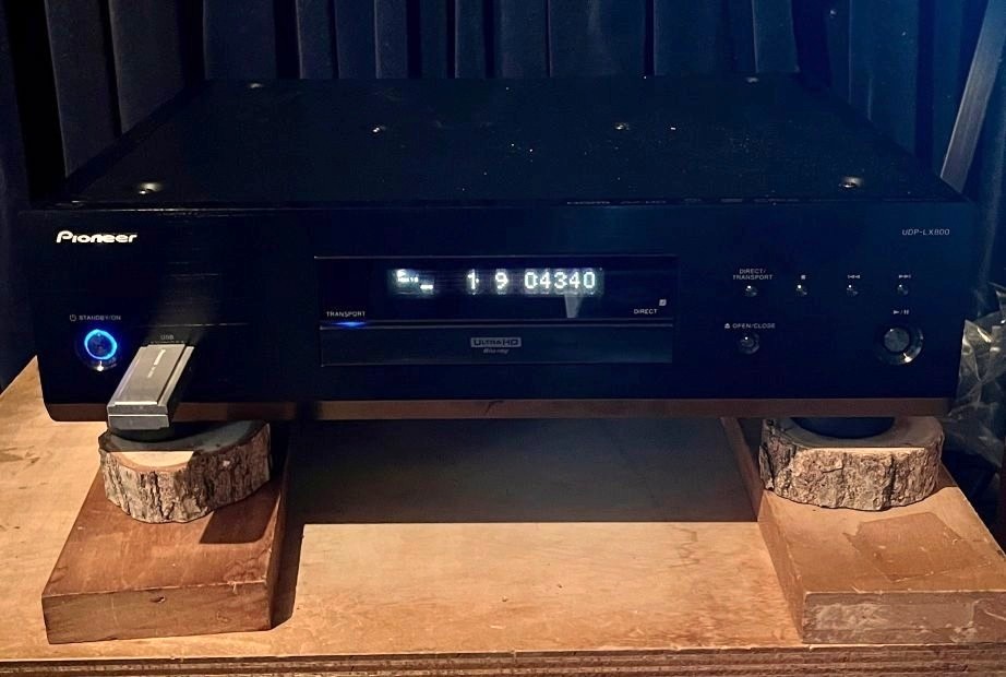 筆者のUDP-LX800の設置法。本体の脚をクヌギの輪切りで受け、さらに前後に渡した硬い集成材の板で受ける。置き台は21mm厚のシナ合板製