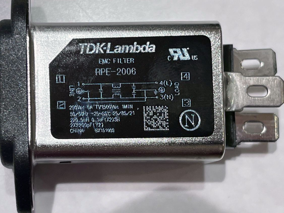 TDKのACラインノイズフィルター。3極インレット端子仕様になっている。金属ケースと右端中央のアース端子は直接接続されている