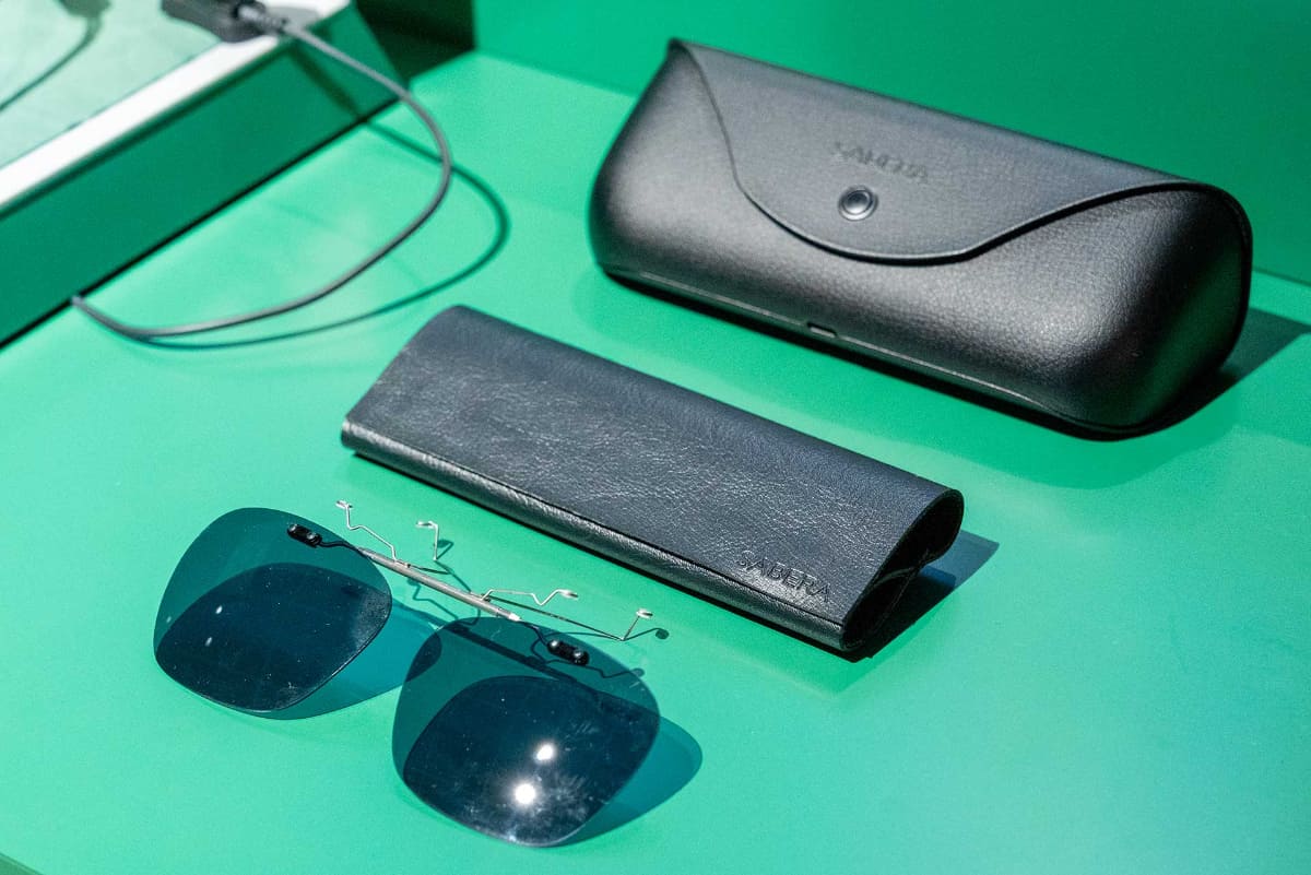 別売りアクセサリーのクリップオン式サングラス(下)とサングラスケース(中央)。画像上は充電器を兼ねた携帯ケース