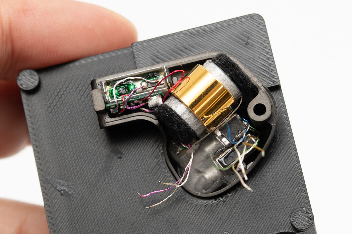 IBUKIの内部。中央の金色のパーツが、ダイナミックドライバー。その左にある長細いパーツがESTのトランス、見えにくいがEST自体は右下にある。さらに、その下にある、黒いものが貼られているのがBAユニットだ