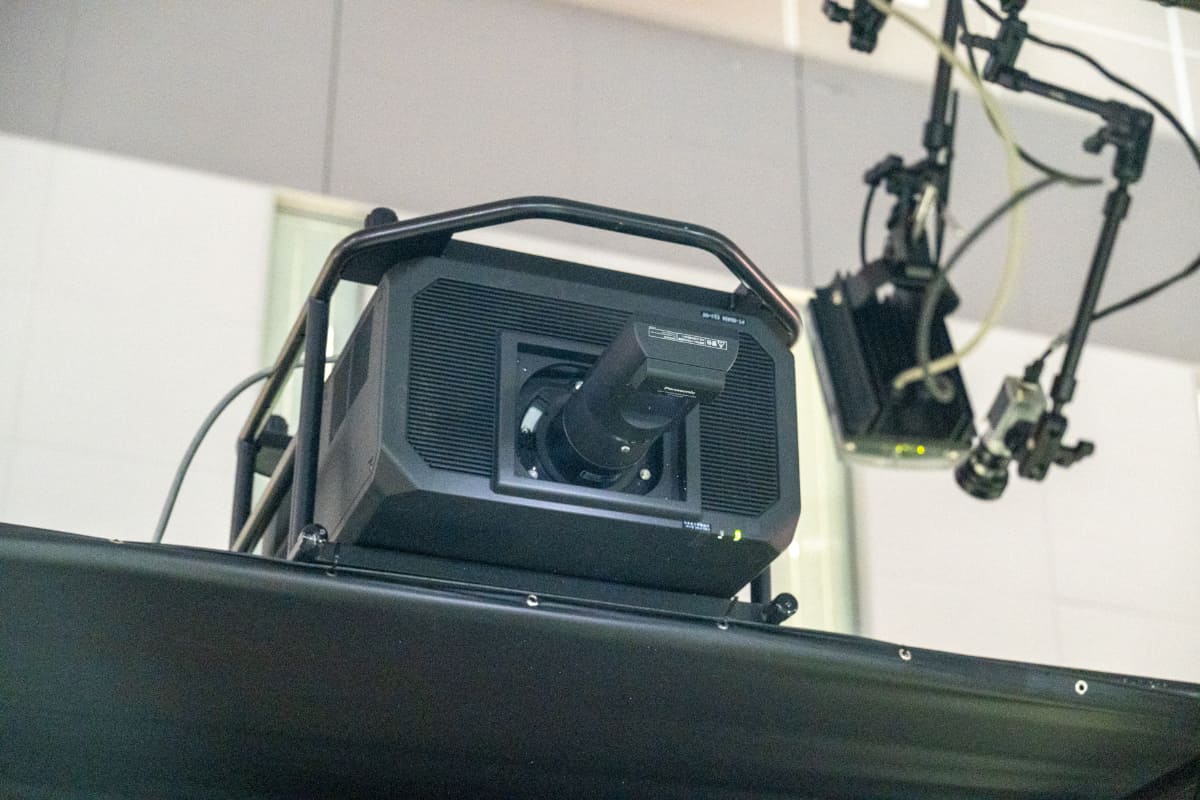 手前の透明度の高いスクリーンに投影しているプロジェクタ