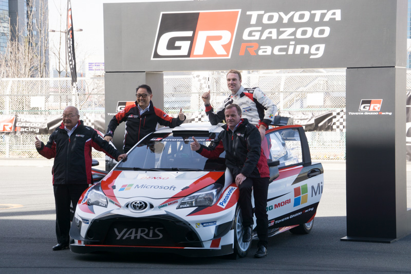デモ走行後に記念撮影に応じるトヨタ自動車株式会社 代表取締役社長 豊田章男氏（左奥）、トヨタ自動車株式会社 専務役員 兼 TOYOTA GAZOO Racing Factory Technical Director 嵯峨宏英氏（左手前）、TOYOTA GAZOO Racing WRT ドライバー ヤリ-マティ・ラトバラ選手（右奥）、TOYOTA GAZOO Racing WRT チーム代表 トミ・マキネン氏（右手前）