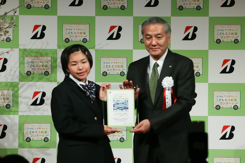 写真左は「すいすい泳げ！みんなで楽しくさんまくん」の作者である八木遥奈さん（12歳）。右はブリヂストン株式会社 執行役副社長 CQMO・品質経営・CSR分掌 石橋秀一氏