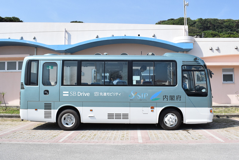 自動走行バスのボディには、内閣府、SIP、先進モビリティ、SBドライブのロゴなどが描かれる