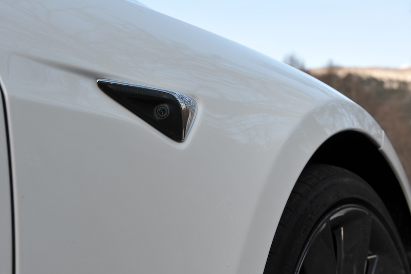 従来ではカメラの数はミニマムで1個（写真上）だったところ、2016年10月後半から生産されているモデルではフロントに3個（写真左）、リアに1個、左右フロントフェンダーおよびBピラー（写真中、右）に各2個という、計8個のカメラが搭載される。写真左はフロントのカメラ、写真中はBピラーのカメラ。また、12個の超音波センサーもバージョンアップされ、以前のバージョンと比べ約2倍の距離までの物体を検知することが可能になったという