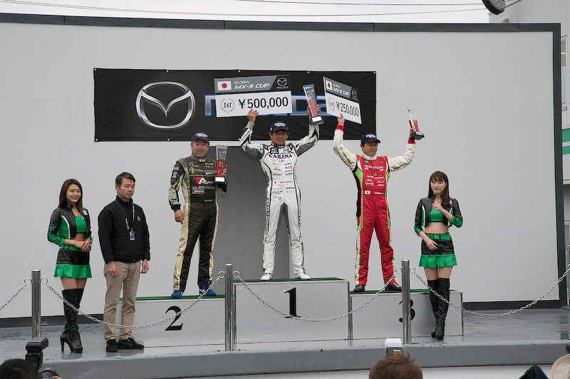 日本初開催のGLOBAL MX-5 CUP表彰式。優勝は7号車の山野哲也選手(CABANA Racing)、2位は56号車 大井貴之選手(Team“Be a racing driver”)、3位は5号車 今村大輔選手(KIMInternational)。優勝した山野選手は暫定表彰式で「イコールコンディションが整っているレースだけに、とても楽しく走れました。今村選手とのバトルも楽しかったし、大井さんを抑え切るのも楽しかったです。途中から雨になりましたが、降り始めはドライのラインを走っていました。しかし雨量が増えてきてからは少しずつ探りながらラインを変えて走り切りました」と感想を語った