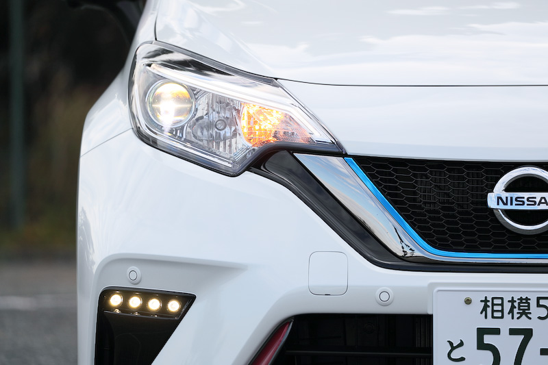 ノート e-POWER NISMOのエクステリアでは専用のフロントグリル、リアバンパー(リアフォグランプ付)、ルーフスポイラー、サイドシルプロテクター、LEDハイパーデイライト(車幅灯連動)、シャークフィンアンテナを装備。また、NISMO仕様らしくフロントクロスバー、フロントサスペンションメンバーステー(トンネルステー)、トンネルステー、リアサスペンションメンバーステー、リアクロスバーなどでボディ補強を行なうとともに、専用チューニングコンピューター(VCM)を搭載して独自のアクセルレスポンスや回生力を実現。足下は16インチアルミホイールに横浜ゴム「DNA S.drive」(195/55 R16)を組み合わせる