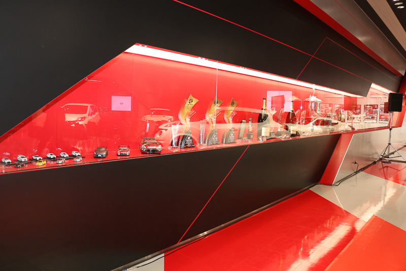 ショールームの壁面側には、これまでのレース活動で手にしてきたトロフィーやレーサーが着用したレーシングスーツなどの記念品を展示している