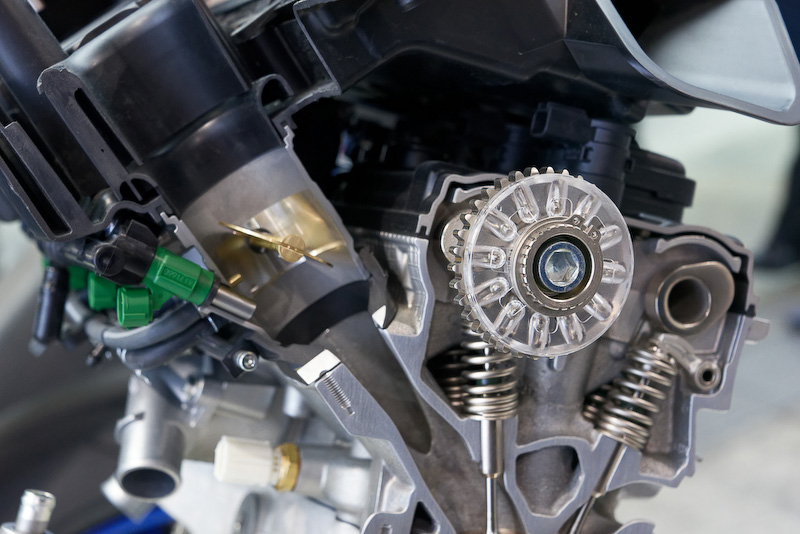 半透明の円形のものが「スズキレーシング VVT」。カムの回転の遠心力でボールが移動し、偏心して位相をずらすことでカムタイミングを変える。2次バランサーは廃止し、エンジン出力のロスを減らした。これによって大幅に振動が増えることはないとのこと