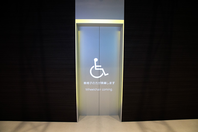 2016年は駐車場内の案内表示などで紹介していたアニメーションライティング誘導システムを、今年はビルなどの案内表示に使って展示。エレベーターのセットが用意され、内部の状況をカメラで把握して、エレベーター内に車いす利用者がいるという設定。エレベーターが目的階に到着する前に、扉にアニメーションを投影して車いす利用者が降りることを表示。その後、出入り口の空けてほしいスペースを表示することで、エレベーター利用者がスムーズの乗り降りできるようにするというデモ内容。投影にはプロジェクターを使用している