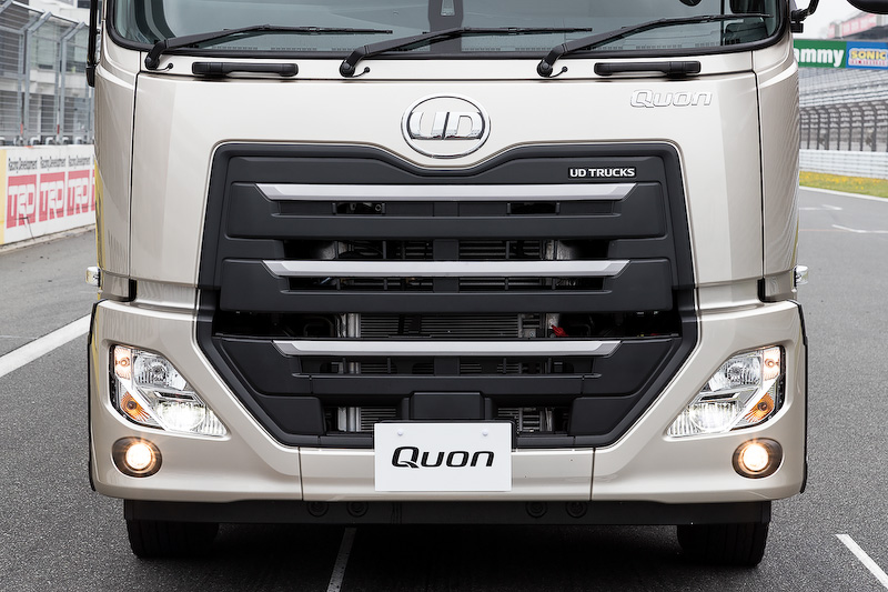 新型クオン(CD冷凍バン)の内外装。操舵輪が前1軸で、後2軸のうち前軸だけが駆動輪を受け持つことから「6×2」と呼ばれている。なお、新型クオンに搭載されるトランスミッションは「ESCOT-VI」と呼ばれる12速AMTとなるが、このAMTとGPSが連動し、1度走行した道路の勾配などを記憶して次回に走る際に省燃費運転に寄与する「Foretrack(フォアトラック)」機能を搭載。クルーズコントロールを用いて60km/h以上で走行している際、同じ登降坂路を走行したときに車速、エンジン回転数、補助ブレーキなどを自動制御し、ドライバーのスキルを問わずだれでも簡単にエコドライブが行なえるようになっている