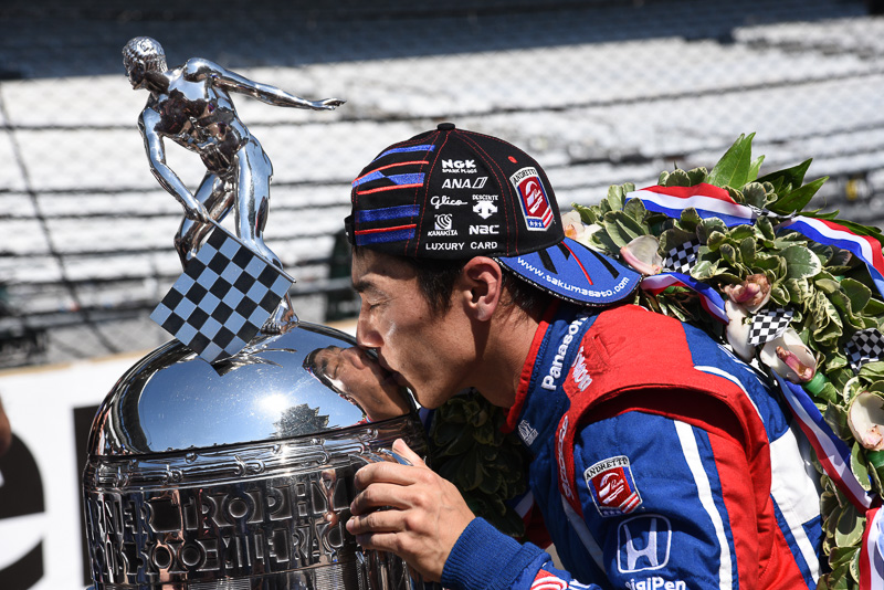 インディ500の優勝トロフィーにキスをする佐藤琢磨選手。琢磨選手のキャップに「glico」の文字が見える