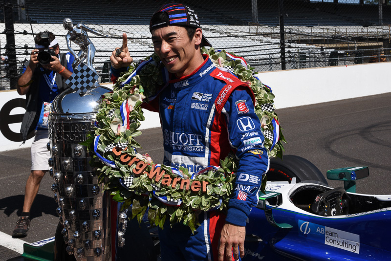 インディ500の優勝トロフィーと佐藤琢磨選手。琢磨選手の左袖やキャップに「ANA」の文字が見える