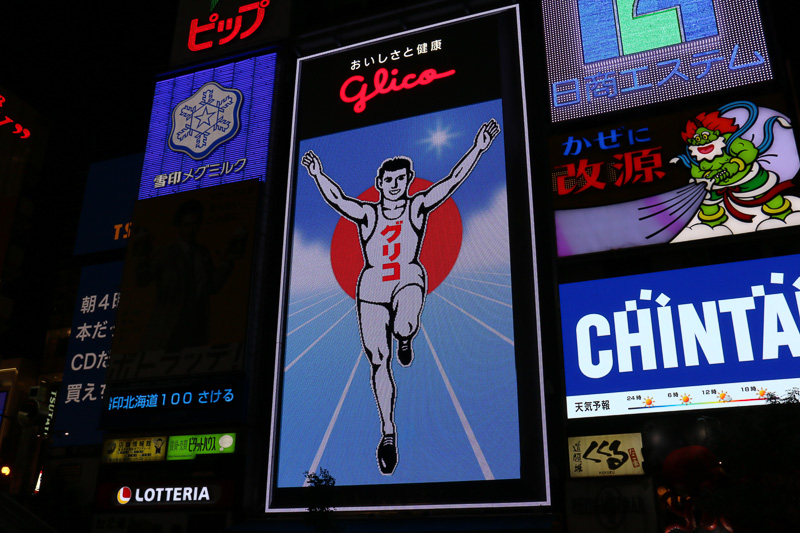 日没後に点灯したあとも、グリコサインはしばらく通常の演出を実施。2014年から6代目にリニューアルした現在のグリコサインは14万個のLEDを照明に使っており、ゴールを駆け抜けていたり、時間帯が朝から夜に移り変わるといったアニメーションを披露している