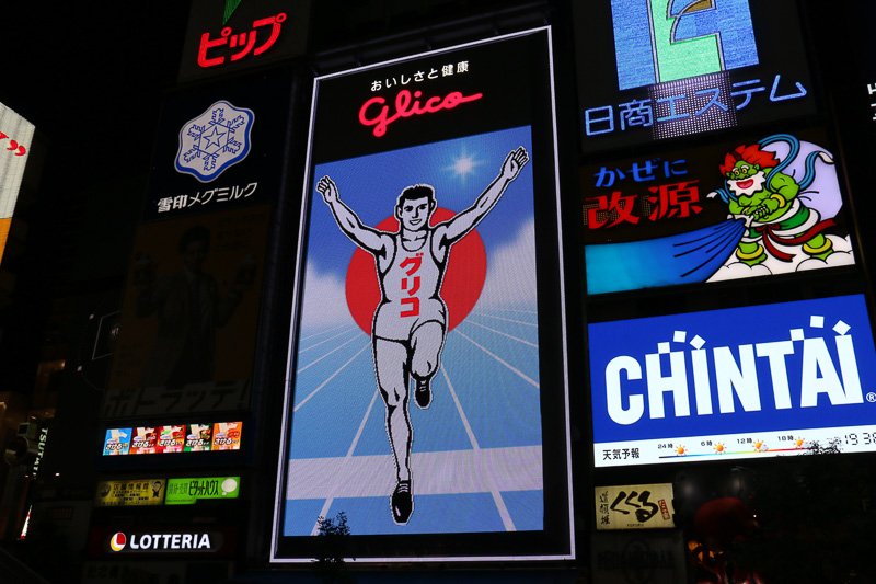 日没後に点灯したあとも、グリコサインはしばらく通常の演出を実施。2014年から6代目にリニューアルした現在のグリコサインは14万個のLEDを照明に使っており、ゴールを駆け抜けていたり、時間帯が朝から夜に移り変わるといったアニメーションを披露している