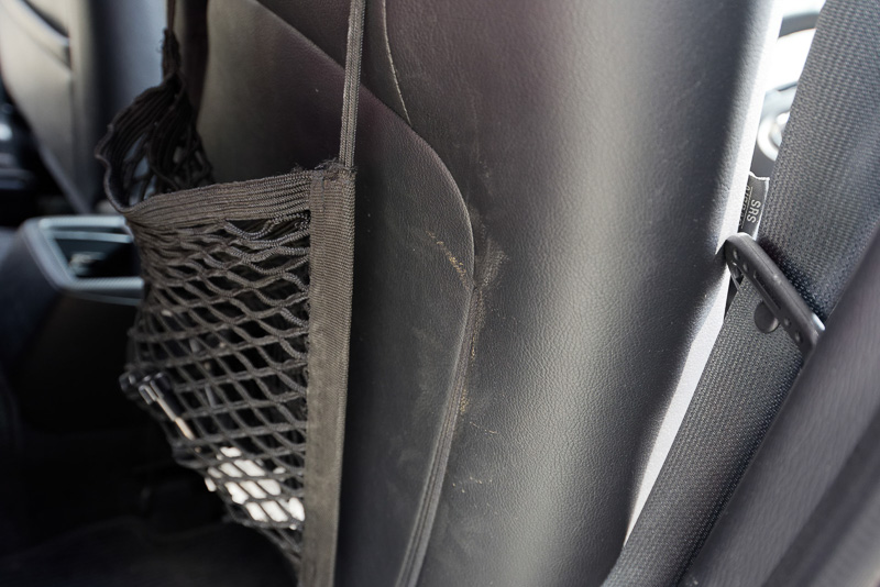 蹴られて薄汚れた運転席のレザーシート背面