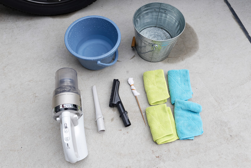 マイCX-3の内装をクリーニングするために用意したアイテム。水で満たしたバケツ×2、柔らかい布×4（1枚は予備）、充電式掃除機、狭い場所を掃除するための布を巻いた棒。今回のクリーニングのために新たに購入したのは数百円の中性洗剤だけだ