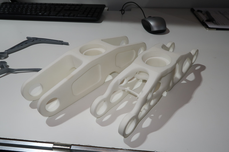 それぞれ左側が人間が設計したパーツで、これをもとに、3D CADで条件を入力し、強度などの要件を維持しながら大幅に軽量化した例。金属製のパーツは0.7kgから0.295kgと半減以下となっている。ここでは金属、樹脂ともに3Dプリントで構成しているが、マシニング、鋳造などで製作する場合もそれぞれの条件を満たす形状の最適化が行なわれるという