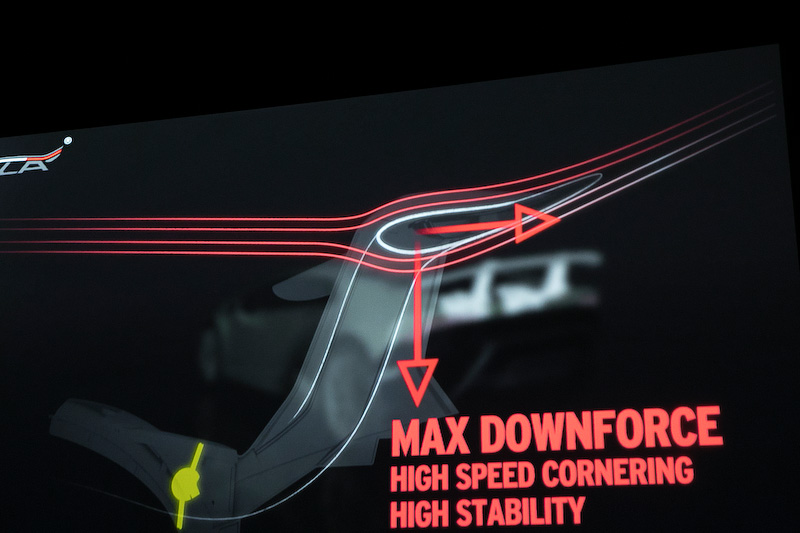 リアウイングの働きについてのスライド。ウイング内のダクトを通った空気はウイング下面のスリットから排出されるときにウイングの空気の流れを変化させてドラッグを軽減する