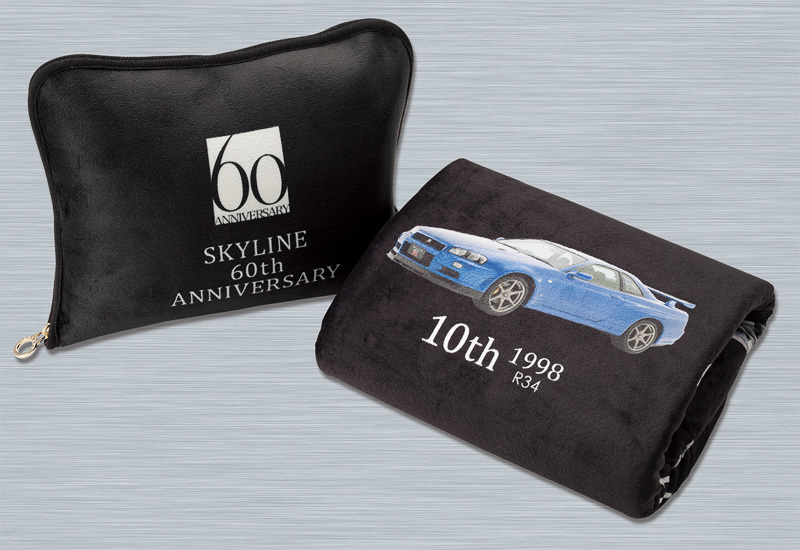 表面にマイクロファイバー起毛を用いた「カバー付きアートケット」。裏面にフリース素材を採用してブランケットとして使用できるほか、専用カバーに収納すればクッションとしても使用可能。写真は「スカイライン60周年記念デザイン」（6500円）