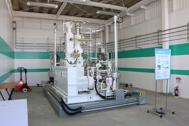 水素上屋棟の右側にある水素圧縮機。4段圧縮で0.4MPaの「低炭素な水素」を45MPaまで昇圧する。圧縮機は2軸縦型のコンパクトな設計となっている