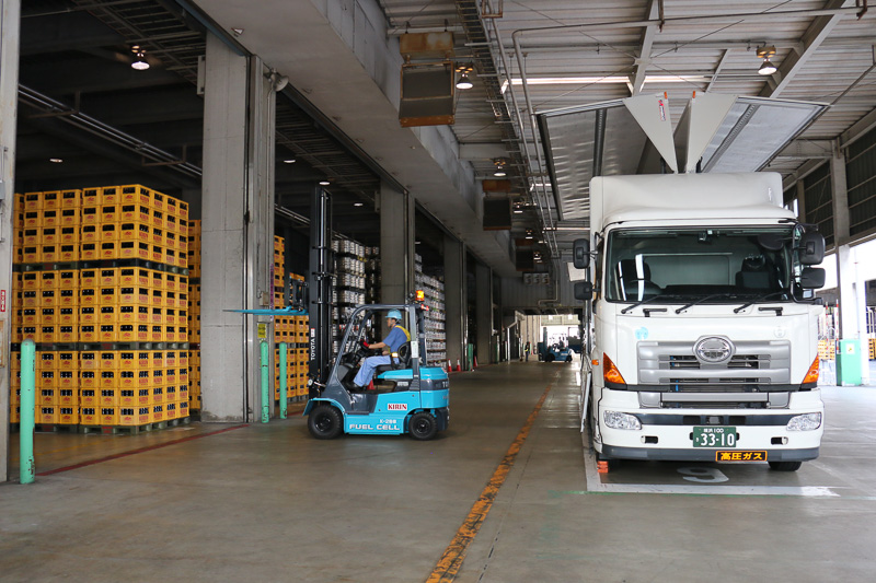 FCフォークリフトの稼動デモでは、2台のFCフォークリフトがくるくると軽快にウイングトラックの周囲を走りまわり、パレットに載せられたビールケースを次々とウイングトラックに運び込む姿が披露された