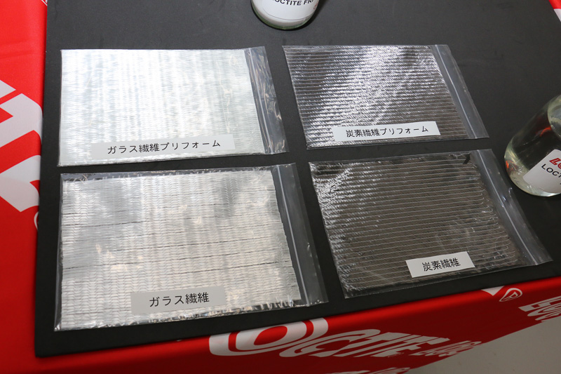 手前側がガラス繊維やカーボン繊維をただ重ねたもの。奥は重ねた部材にヘンケルのポリウレタンやエポキシとの相性を整えたバインダー「LOCTITE FRP 2000」を含ませて「プリフォーム」という状態にした部材
