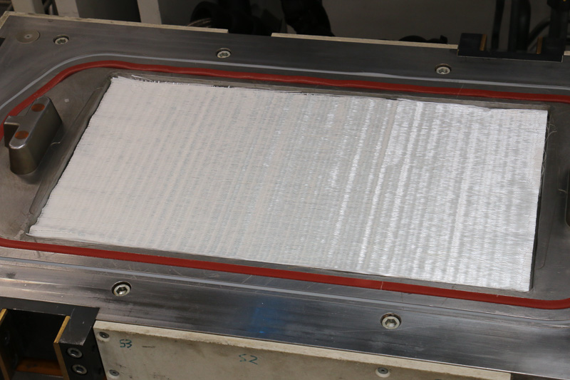 成型実演がスタート。まずはガラス繊維プリフォームを大型成形機の金型にセット