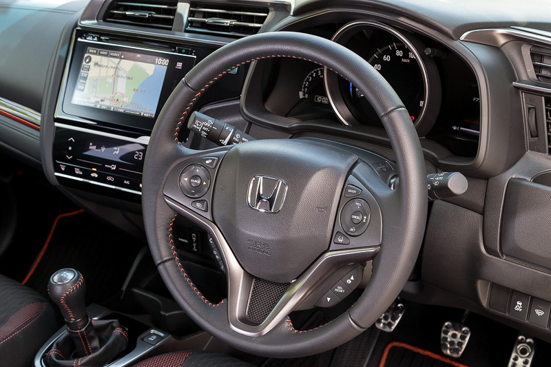 RS Honda SENSINGのインテリアでは、ブラック×オレンジのスポーティシートに加え、インパネ加飾やステアリング＆シフトノブのステッチ、ドアトリムなどにオレンジの加飾を使って活発なイメージを表現する