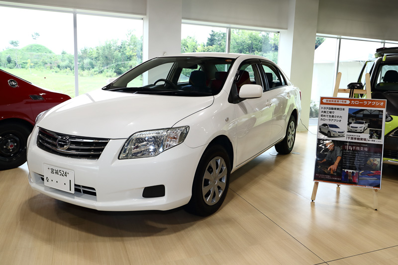 白いカローラ アクシオ（10代目）は宮城大衡工場で生産された最初の1台。シートカバーは宮城県栗原市の若柳地織で、なんと100年前にトヨタグループの創始者 豊田佐吉氏によって発明された機械を使って生産を始めたという織物。その機械は今なお使い続けられているそうだ