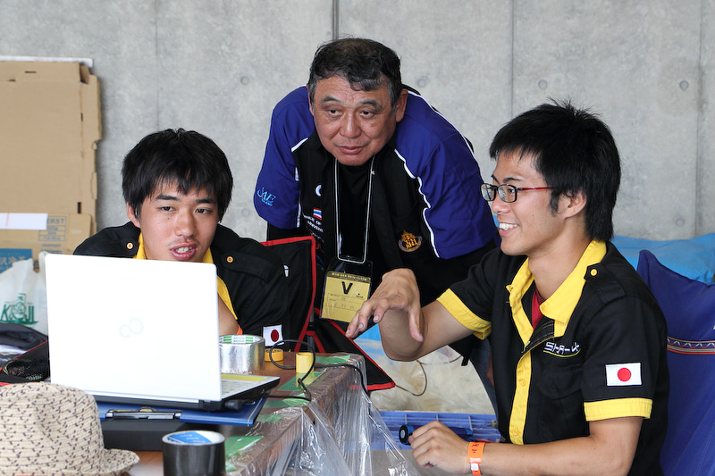 山口東京理科大チームで指揮を執る貴島孝雄氏（写真左）は、マツダ ロードスターの開発主査。ホンダ NSXの開発ドライバーだった玉村誠氏（写真中）は、タイのPrince of Songkla Universityにボランティアで技術指導している。玉村氏は、声がかかれば自身が日ごろ指導しているチームでなくても気軽に出向いて指導していた。写真右は芝浦工業大学のピットで学生と語り合う玉村氏