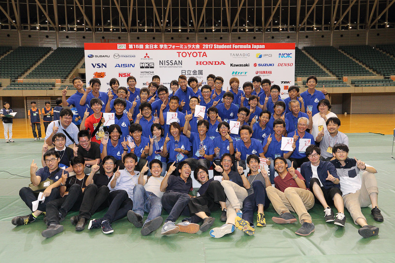第15回全日本学生フォーミュラ大会2017の頂点に立った京都工芸繊維大学。最前列に並んだOBも昨年に総合優勝を勝ち取ったメンバーで、同校は2連覇を達成した