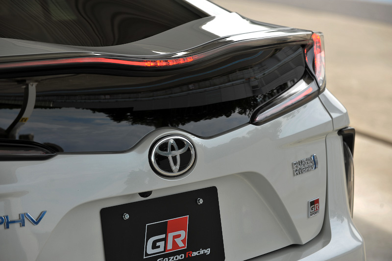 プリウス PHV GR SPORTは、エクステリアでは水平/垂直の｢Functional MATRIX｣グリルや専用バッヂなどを装着するほか、ホワイト塗装＋GRロゴ入りのブレーキキャリパー、専用チューニングサスペンションの装着、ブレースの追加が行なわれている