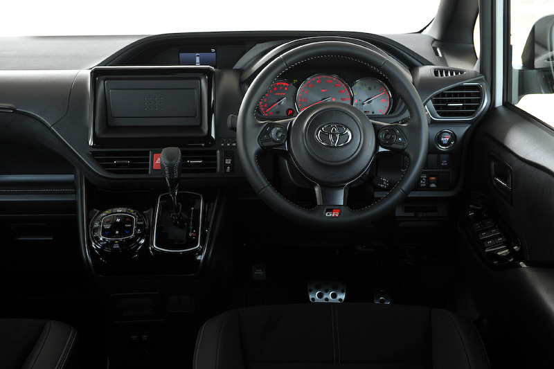 ヴォクシー GR SPORTのインテリア。メーター（GRロゴ付）、アルミペダル、小径ステアリングホイール、本革巻きシフトノブ（ディンプル＋シルバーステッチ）などを専用装備する