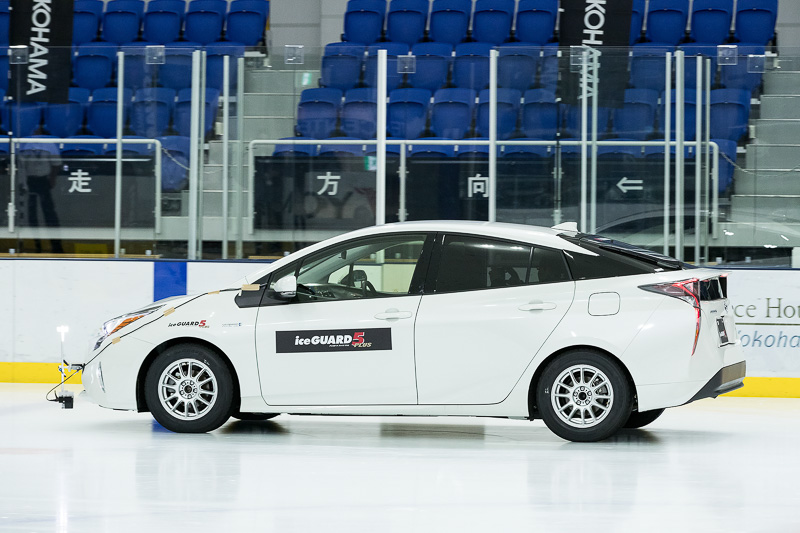 アイスガード 5プラス（白いプリウス）と、アイスガード 6（黒いプリウス）の制動距離の違い。20km/hからのブレーキで、壁の青いペイントからアイスガード 6の制動距離が短いことが分かる