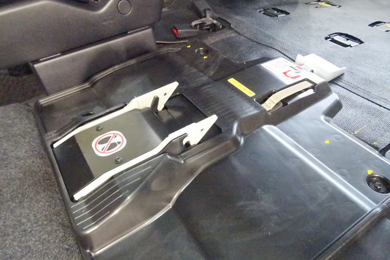 中央に見える白いフックで電動車いすをガッチリとロックする。後方側の白いペダルを踏むと電動車いすがリリースされる